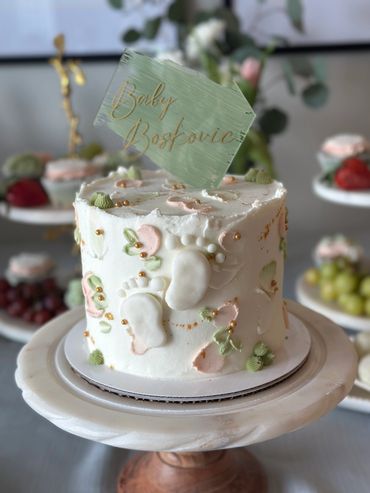 Elegant baby shower cake with pastel decorations and an acrylic cake topper. 