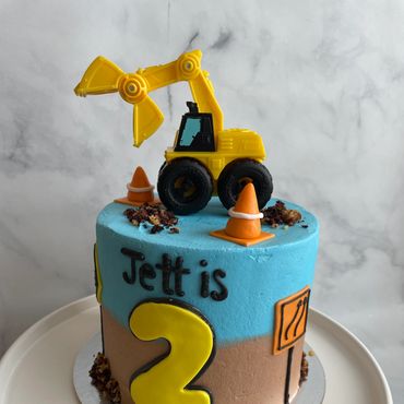 Construction theme kids cake with fondant details and a toy on top. 