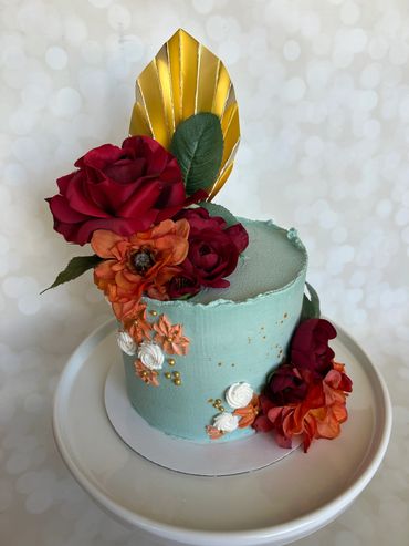 Buttercream cake with silk florals and gold fan. 