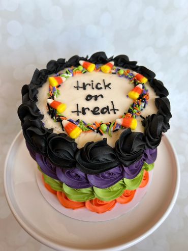 A festive Hallowen cake with candy corn and bright green, purple, orange and black buttercream. 