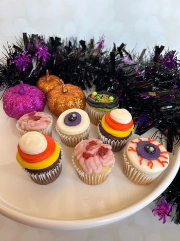 Decorated mini cupcakes for Halloween with an eyeball, brain, cauldron and candy corn. 