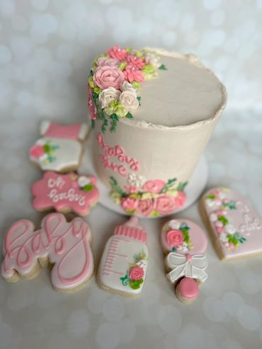 Decorative baby shower cake with matching themed cookies in pink and white.