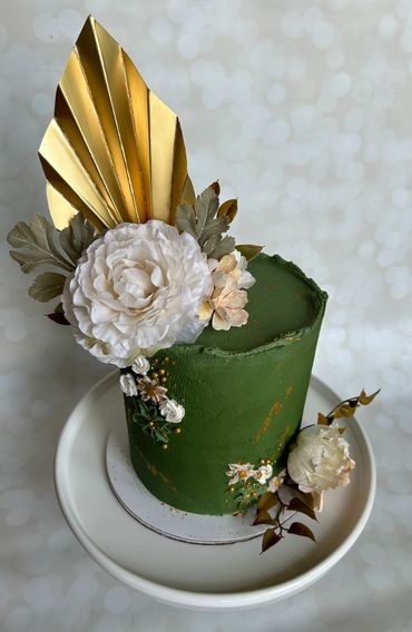 Deep green birthday buttercream cake with silk florals, painted buttercream and a gold palm frond. 