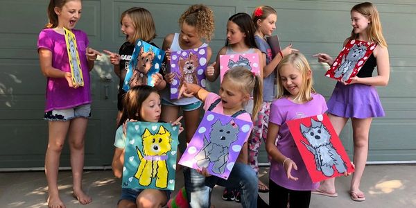 Group of girls excitedly showing their colorful dog paintings outdoors.