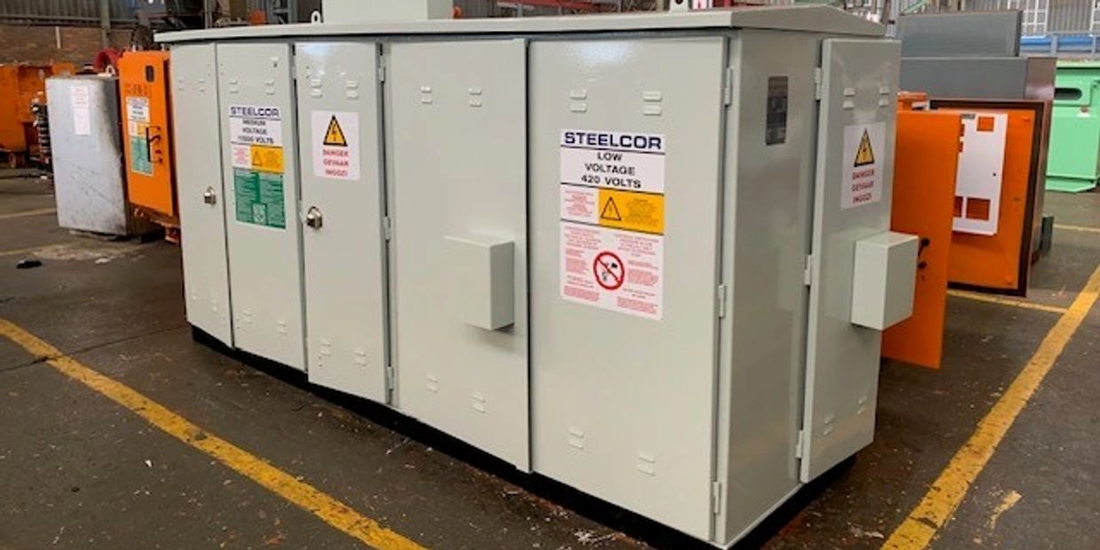 Industrial low voltage electrical cabinet labeled STEELCOR in a factory setting.