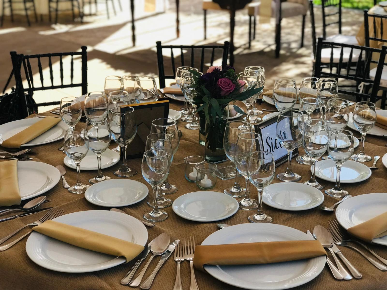 Elegantly set round dining table with glassware and floral centerpiece.