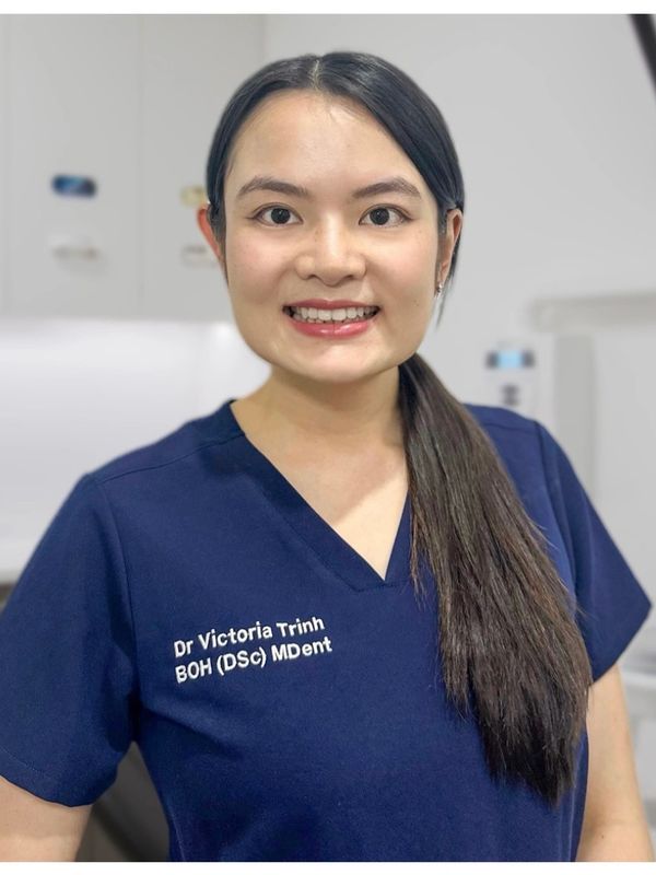 Dr. Victoria Trinh in navy scrubs smiling confidently.