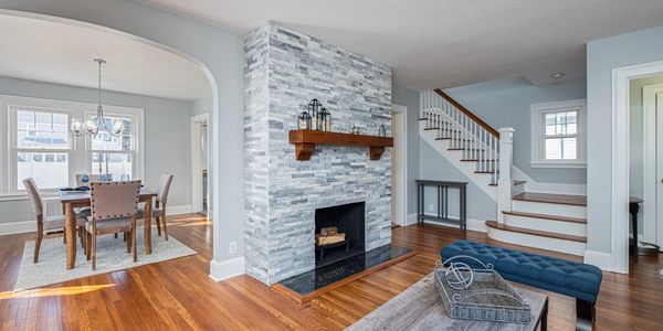 Bright living room with stone fireplace and wooden floors.