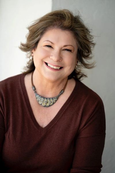 A woman wearing a brown sweater and a decorative necklace