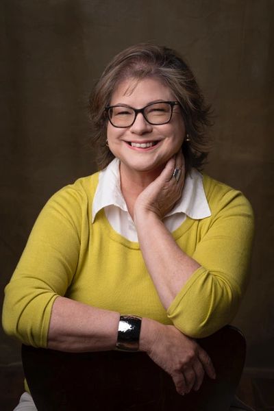 A woman wearing a bright yellow sweater and a white collared shirt