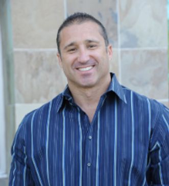 Smiling man in a blue striped shirt posing outdoors.