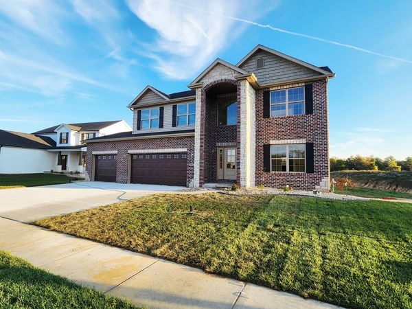 Modern two-story brick house with a large driveway and well-maintained lawn.