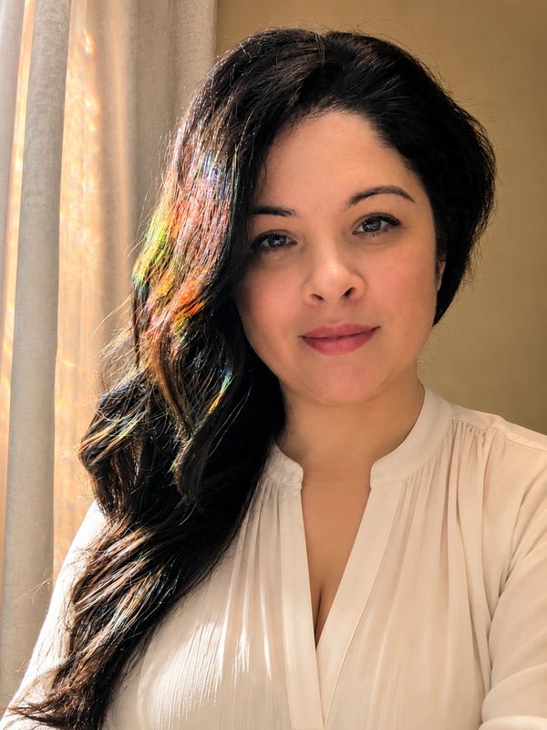 Woman with long dark hair and white blouse.