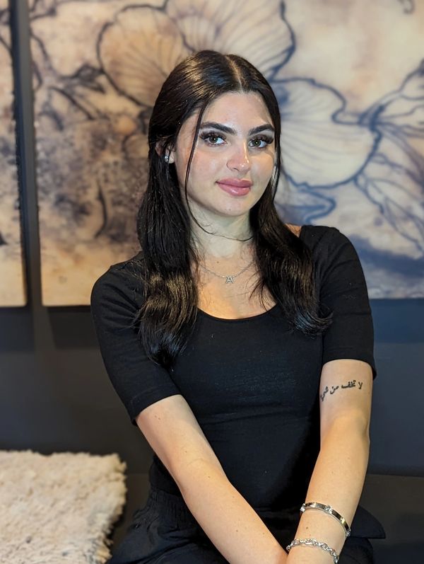 Young woman with black hair and tattoo on her arm.