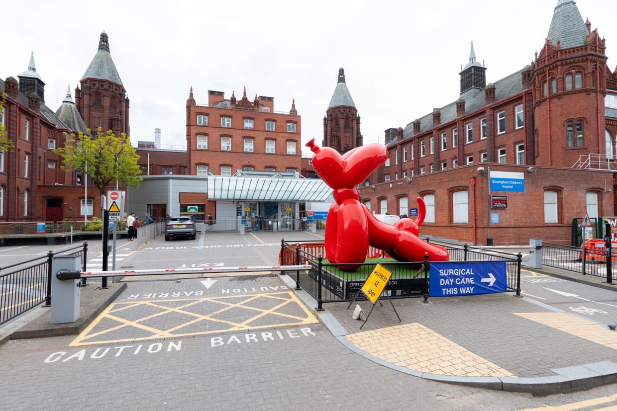 Large red balloon dog sculpture outside Birmingham Children's Hospital.
