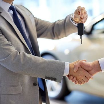 Two businessmen shaking hands while handing over car keys.