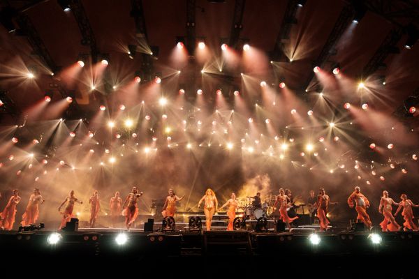 A grand stage performance with dancers and vibrant lighting effects.