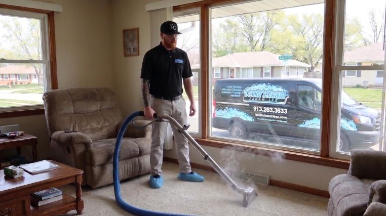 Professional cleaner using a steam carpet cleaner in a living room.