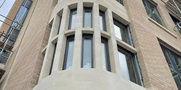Curved building corner with vertical windows and brick facade.