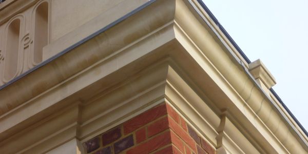 Close-up of a building's corner with brick and detailed beige trim.