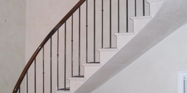 Curved staircase with white steps and dark wooden handrail.