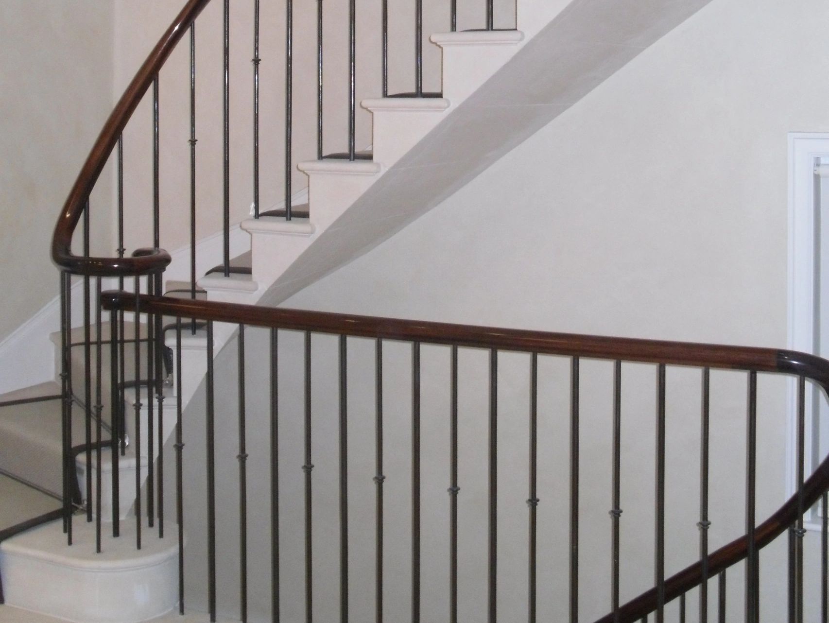 Close-up of a staircase with dark metal railings and wooden handrails.