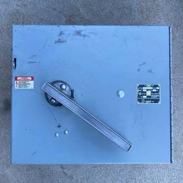 Gray metal electrical switch box with a large handle and labels.