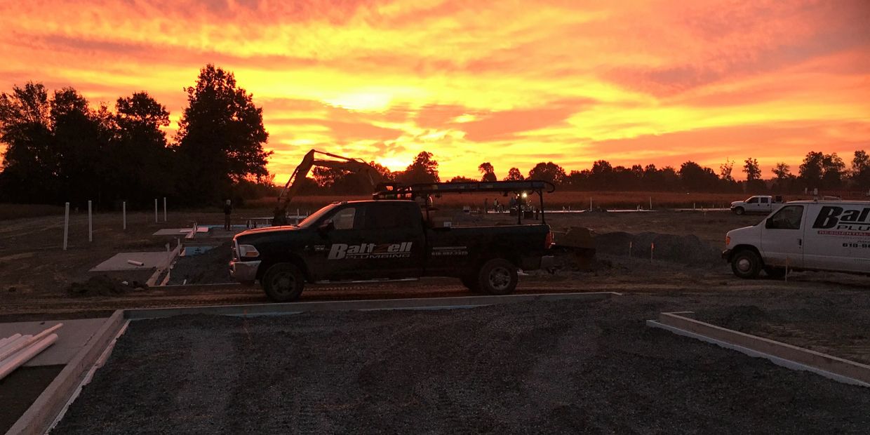 Sunset over a construction site with trucks and machinery.
