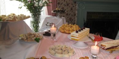 A table set with various desserts and candles in a cozy room.