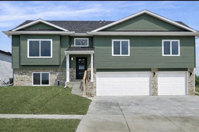 Modern green and stone two-story house with three-car garage.