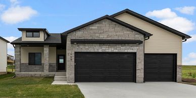 Modern house with stone and siding exterior and black garage doors.