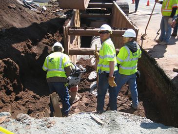 Workers standing in construction trench.