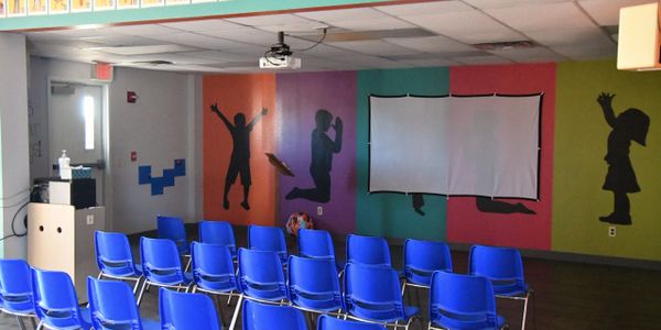 A colorful room with blue chairs and silhouette wall art.