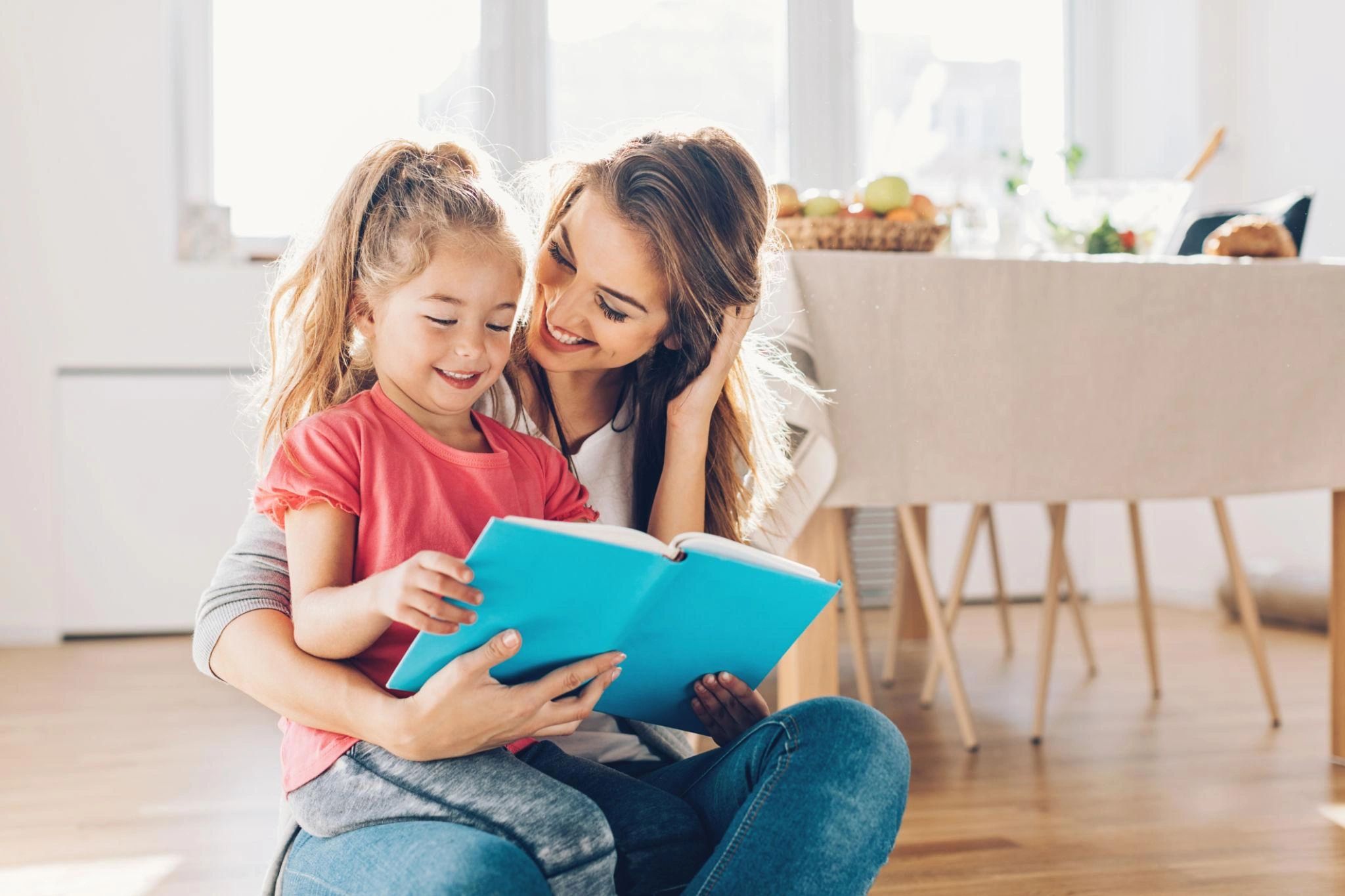 Mother and daughter happily reading a book together.
