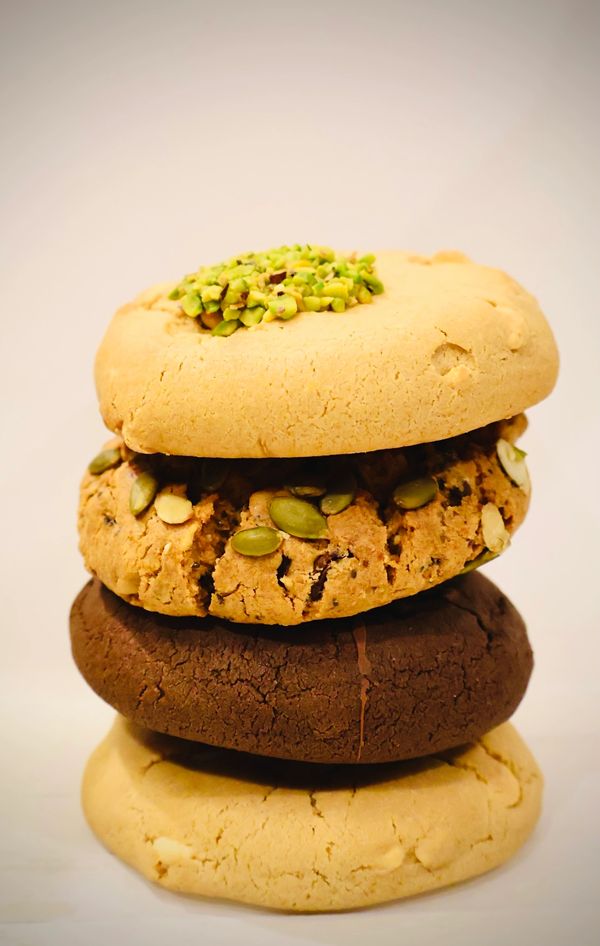 Stack of four assorted cookies with nuts and seeds on a white background.
