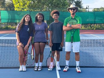 Group of tennis players posing on court.