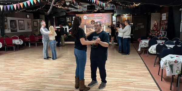 Couples dancing in a decorated room with festive banners and lights.