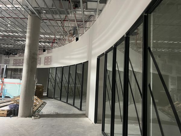 Interior of a building under construction with curved glass walls and exposed ceiling.