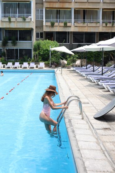 Femme en maillot et chapeau montant une échelle de piscine.