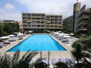 Piscine extérieure d'un hôtel avec chaises longues et parasols.