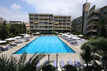 Piscine extérieure d'un hôtel avec chaises longues et parasols.