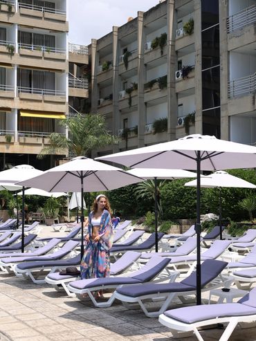Femme en sortie de piscine près de transats et parasols.