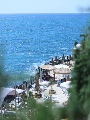 Une terrasse avec chaises longues et parasols au bord de la mer.