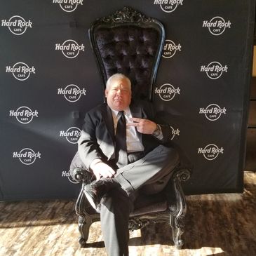 Man in suit sitting on a throne chair at Hard Rock Cafe.