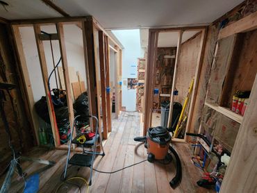 Interior of a house under renovation with exposed wooden framing and construction tools.
