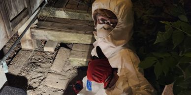 Person in protective suit and mask gives thumbs up outdoors at night.