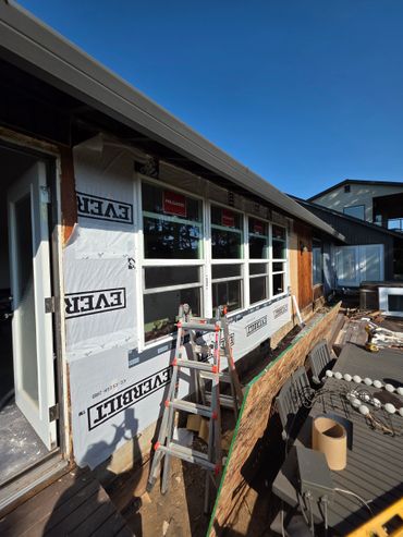 House exterior under renovation with new windows and construction materials.
