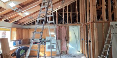 Interior of a house under renovation with exposed wooden beams and ladders.