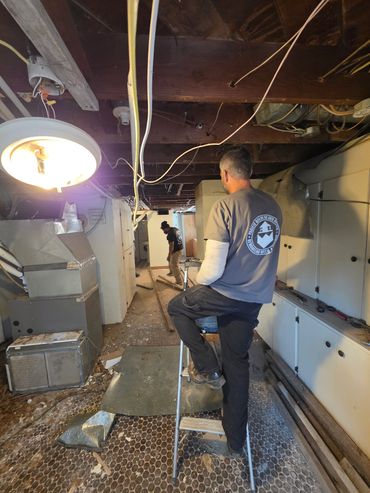 Worker standing on a step ladder in a basement.