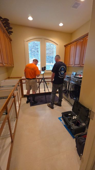 Two men setting up equipment in a laundry room.